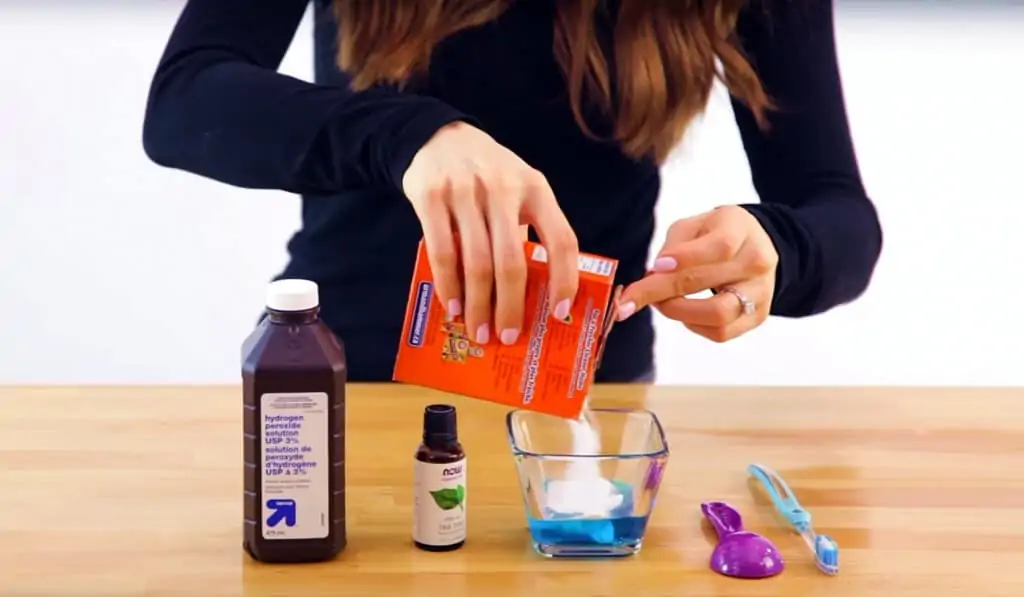 Hands mixing tile scrub ingredients in a bowl